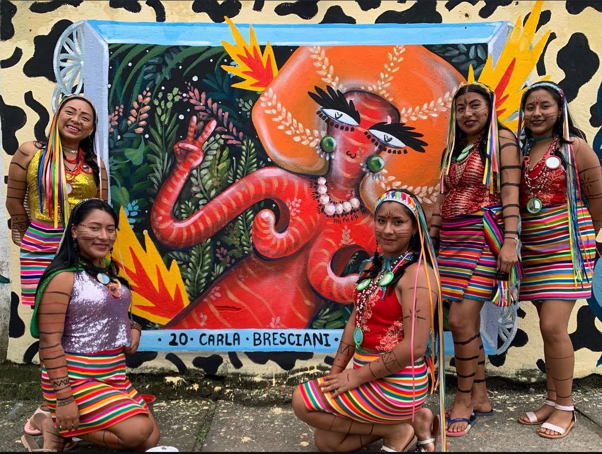 Carla Bresciani junto a mujeres de la comunidad Tsáchila frente al mural